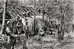 Rocky Williams foreground stands guard while Timorese natives build a bamboo hut