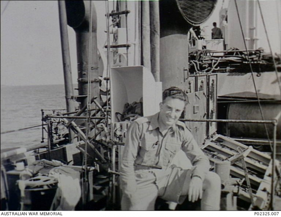 P02325.007 – c. September 1945 - Arafura sea.  Informal outdoor portrait of Sergeant Keith B. Davis, Military History Section (MHS) official photographer, sitting on the deck of HMAS Parkes.png